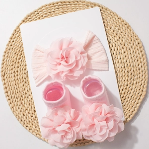 Detailed view of pink knitted baby headband and socks set with chiffon flowers