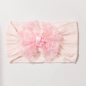 Détail du bandeau rose côtelé pour bébé avec nœud en maille et broderie de dentelle