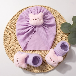 Lavender baby accessory set with cute piglet knit hat and matching socks on woven mat