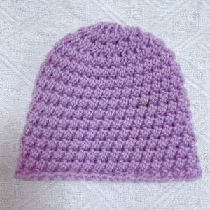 Detail view of light purple hand-crocheted baby beanie with thick knit texture and soft yarn