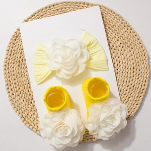 Close-up of yellow baby headband and socks set featuring large white chiffon flowers