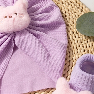 Close-up of purple baby hat and socks set featuring cute 3D knit texture and plush pig decor
