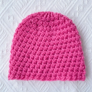 Detail of rose pink chunky knit baby beanie with textured crochet pattern for warmth