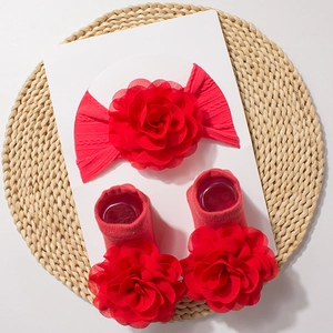 Detail view of red baby floral headband and socks set on a circular woven mat
