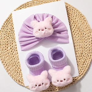 Detail of baby soft knit hat and socks set featuring cute 3D plush pink pig decorations