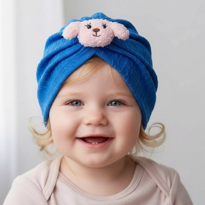 Close-up of bright blue infant turban hat with a cute plush pink puppy patch decoration
