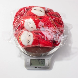 Detailed view of Christmas baby hat and socks set on a scale weighing 73.6g