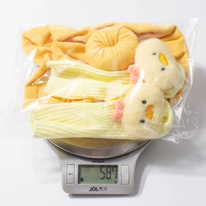 Detailed view of yellow baby sock set with chick motifs being weighed on a scale