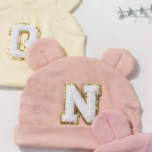 Detailed view of baby modal beanies with cute bear ears and chenille letter patches