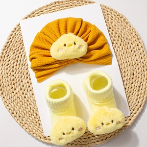 Detailed view of yellow baby turban hat and ribbed socks with cute plush chick face accents