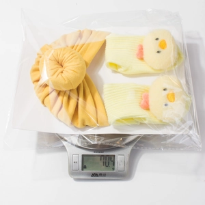Weight measurement of soft cartoon baby hat and socks set in yellow packaging