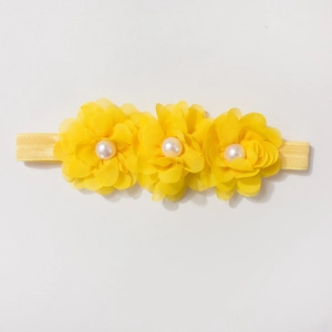 Détails de trois fleurs en mousseline jaune et perles sur un bandeau bébé élastique