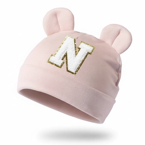 Detail of pink modal baby hat with bear ears and sequined letter N embroidery