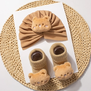 Close-up of khaki infant knit hat and socks set featuring 3D plush teddy bear ornaments