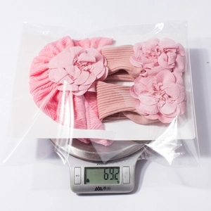 Pink infant headbands and flower accessories set being weighed on a scale, 69.2g