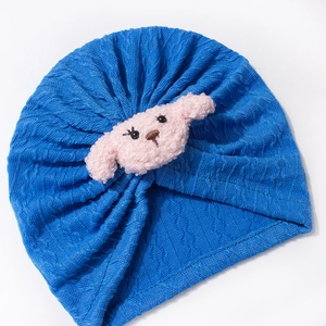 Detail of baby turban hat showing blue waffle knit texture and pink plush dog decor