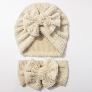Detailed view of the soft beige plush knit baby hat and headband set with large bows