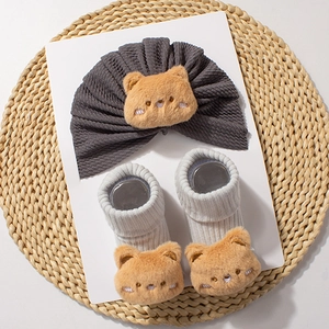 Detail of dark grey baby hat and socks set featuring cute brown plush bear decorations