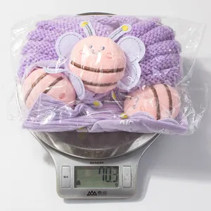 Detail showing baby knit socks set with bee decor on scale weighing 70.3 grams