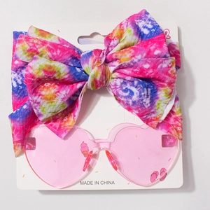 Détail du bandeau bébé avec nœud tie-dye et lunettes de soleil cœur rose à motif glace