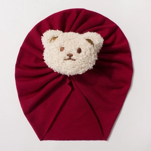 Solid burgundy baby beanie featuring a cream plush bear detail in soft ribbed cotton