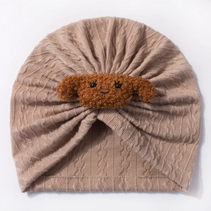 Detailed view of knitted infant turban featuring a brown plush puppy embroidery on soft khaki