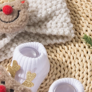 Detailed close-up of knitted baby Christmas headband and socks with 3D reindeer design