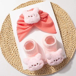 Detail of coral pink baby turban and matching ribbed socks with plush cartoon animal decor