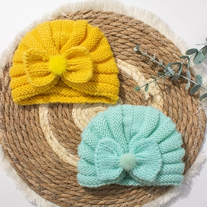 Infant knit beanie hat with cute bow and fluffy pompom in yellow and mint green colors