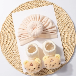 Detail of soft beige baby turban hat and white socks with 3D plush tiger motif set