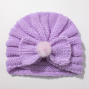 Detailed texture of lavender knitted baby hat with a large bow and pink faux fur pompom