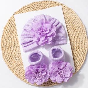 Macro view of purple knitted baby hat and socks with large 3D handmade floral detail