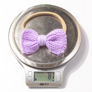 Detail shot showing the lightweight 8.1g weight of the purple knitted bow baby headband