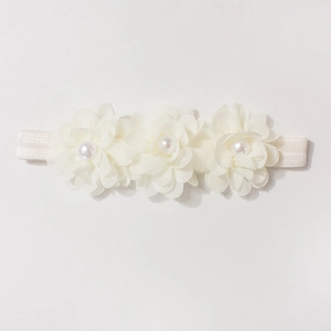 Détail d'un bandeau blanc pour bébé avec trois fleurs en mousseline et perles élégantes