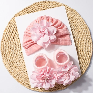 Detailed knit texture of pink baby hat and socks set with 3D handmade floral decor