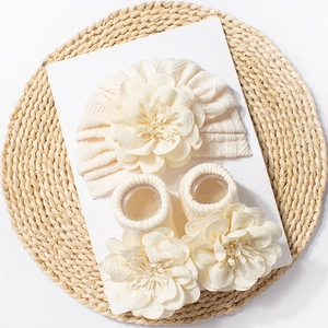 Detail of baby beanie and socks set in cream knit with 3D fabric flower accents