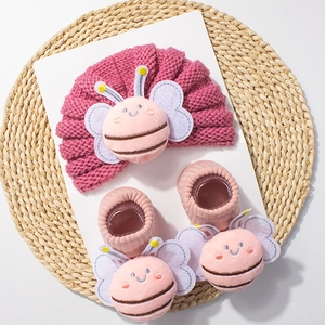 Detail of pink knitted baby hat and socks set featuring 3D cartoon bee plush appliques