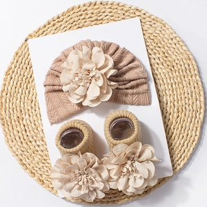 Detail of baby knitted hat and ribbed socks set with 3D flower decor on white card