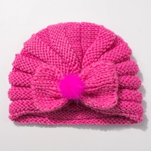 Cozy rose red knit baby hat featuring a large decorative bow and a soft faux fur pom-pom