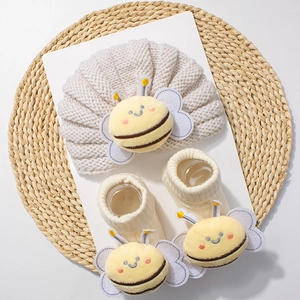Detail view of knitted baby hat and socks set featuring cute plush bee decorations
