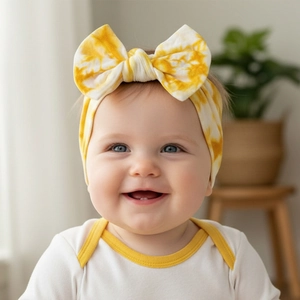 Close-up of yellow and white tie-dye baby headband with a soft oversized bow design