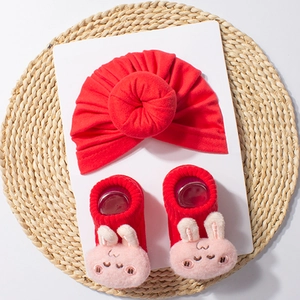 Close-up of soft red baby turban hat and matching socks with plush bunny decor