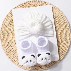 Detail of white infant turban hat and baby socks featuring 3D plush panda embroidery