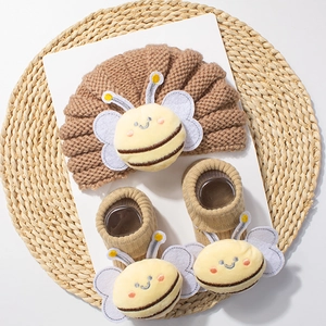 Detail of warm brown knit baby set with adorable plush bee design on hat and socks