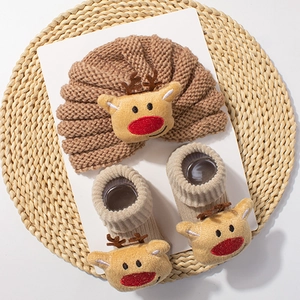 Detail of baby knitted winter set featuring warm hat and socks with cute reindeer decor