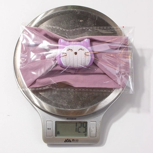Détail d'un bandeau violet pour bébé pesant 12,9g sur une balance électronique