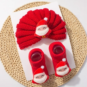 Detail of red knitted Christmas baby hat and socks set with 3D plush Santa Claus decorations