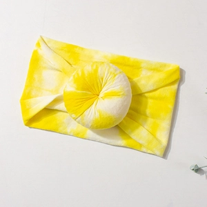 Detail view of yellow tie-dye nylon baby headband with a soft donut knot accessory