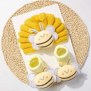 Detailed view of yellow knitted baby turban hat and socks with cute 3D bee decorations