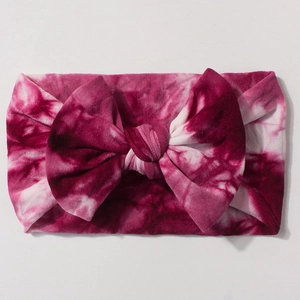 Detailed top view of a large fuchsia and white tie-dye bow on a soft nylon baby headband